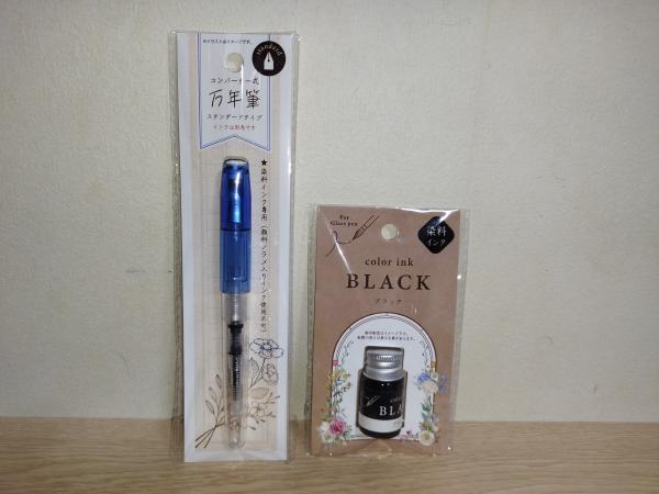 松野工業株式会社のコンバーター式万年筆 スタンダード ブルー(左)とガラスペン用インク ブラック(右)が未開封のまま壁に立てかけられています