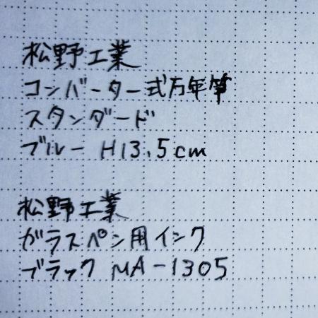 ブラックのインクが入ったコンバーター式万年筆で試し書きをしたメモ帳の切れ端です。メモ帳はクリーム色の紙に薄い灰色で5mm方眼の点線が引いてあります。「松野工業 コンバーター式万年筆 スタンダード ブルー H13.5cm」「松野工業 ガラスペン用インク ブラック MA-1305」と書かれています