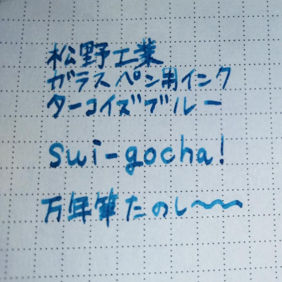 ターコイズブルーのインクが充填されたコンバーター式万年筆で試し書きをしたメモ帳の切れ端。「松野工業ガラスペン用インク ターコイズブルー」、「sui-gocha!」、「万年筆たのしーーー」と書かれている