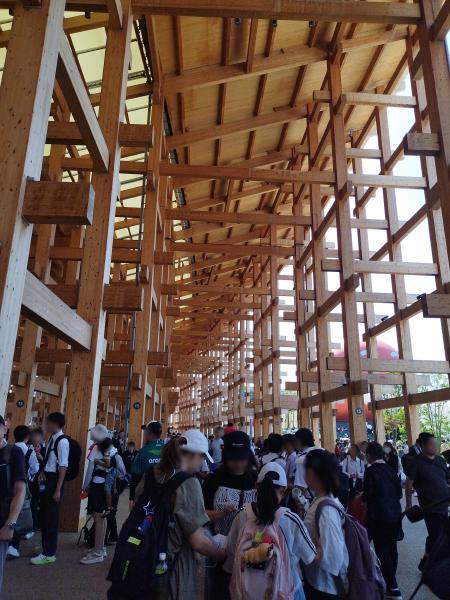 大阪・関西万博のシンボル、世界最大の木造建築「大屋根リング」内の通路を歩く群衆。