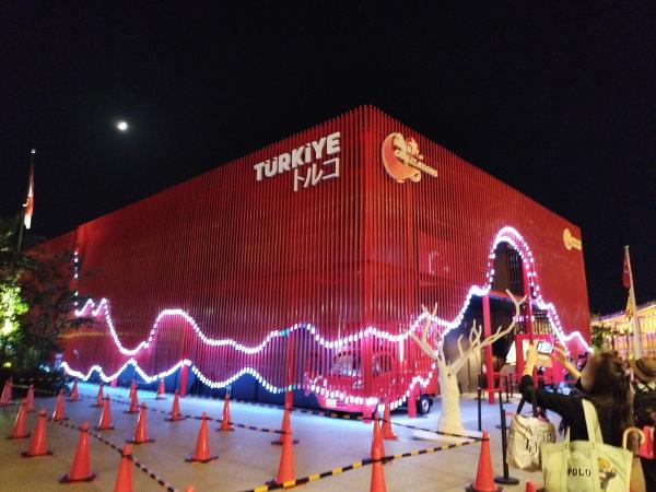 真っ赤な外壁に白い波状のLEDが輝くトルコ館。建物の前にはコーンが並んでいます。