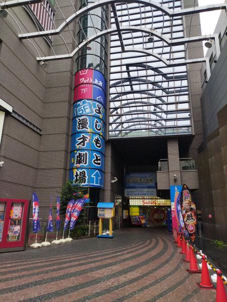 「よしもと漫才劇場」の看板がある、建物への入り口。周りに旗が立っています。