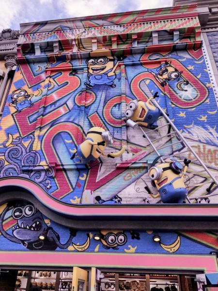 カラフルな壁画で、ミニオンたちが梯子に登ったり、飛び跳ねたりしている賑やかな建物の外観。